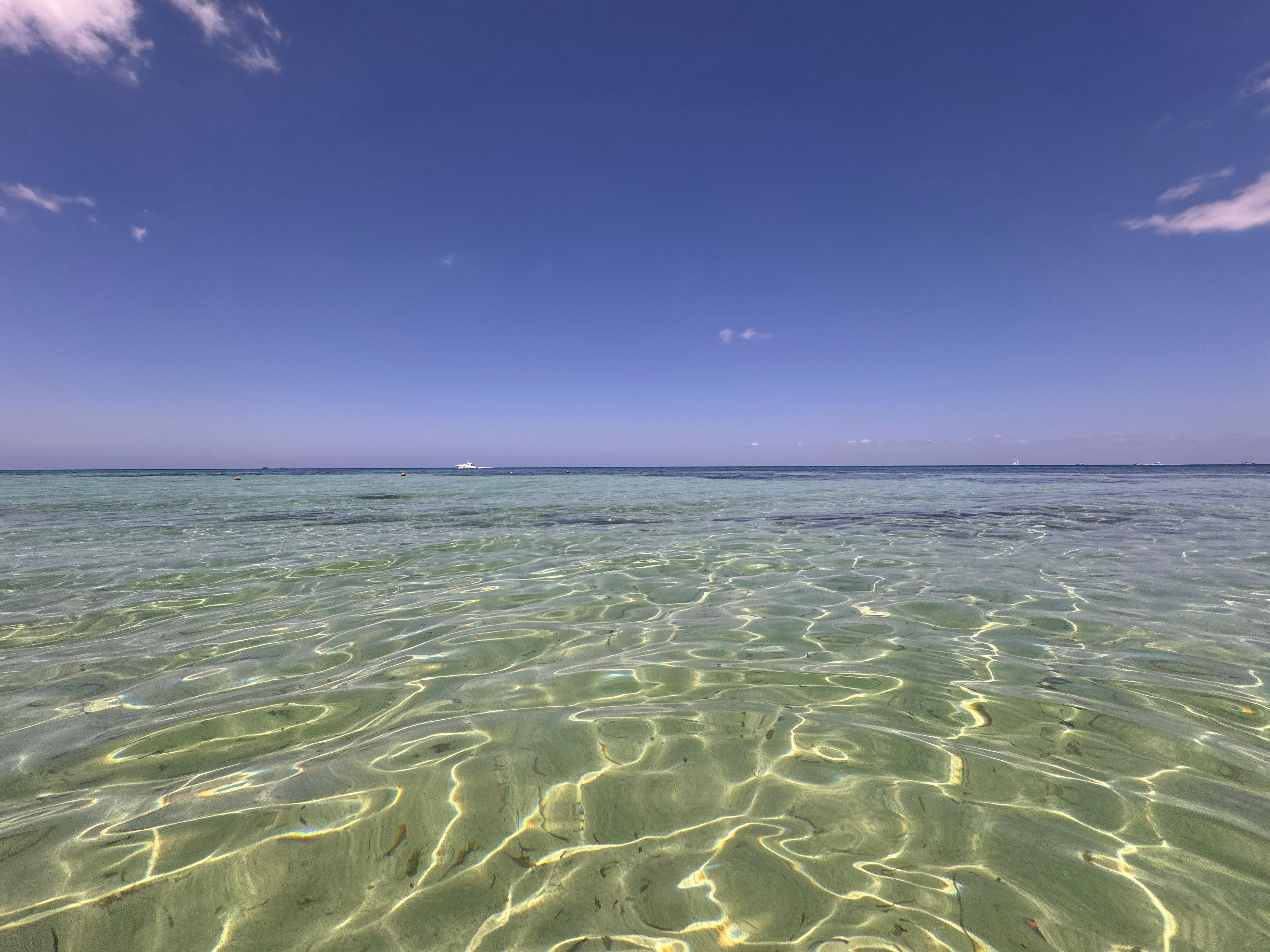 Clear shallow water stretching toward a calm ocean horizon
