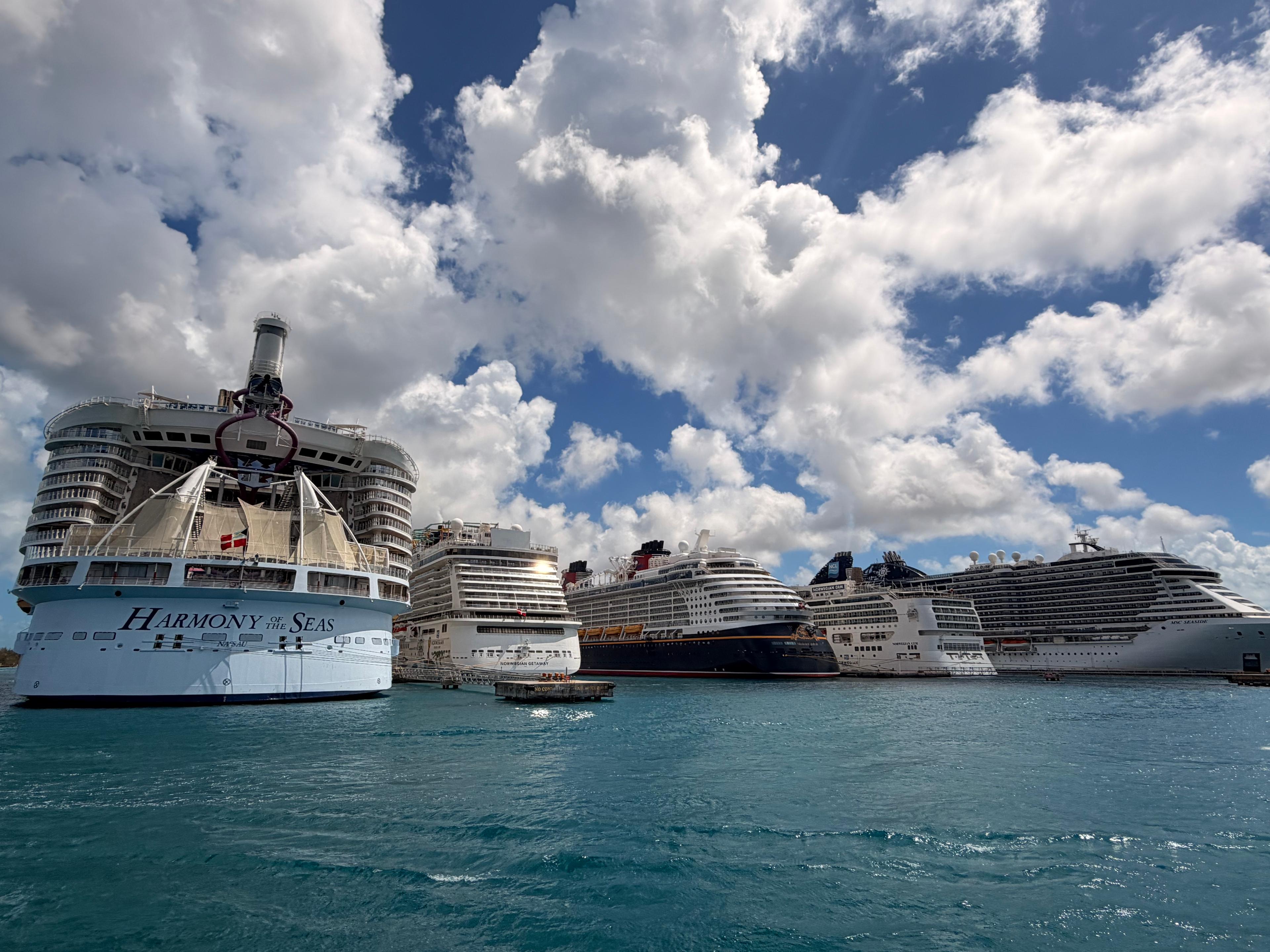 Several cruise ships gathered in a harbor beneath a bright sky
