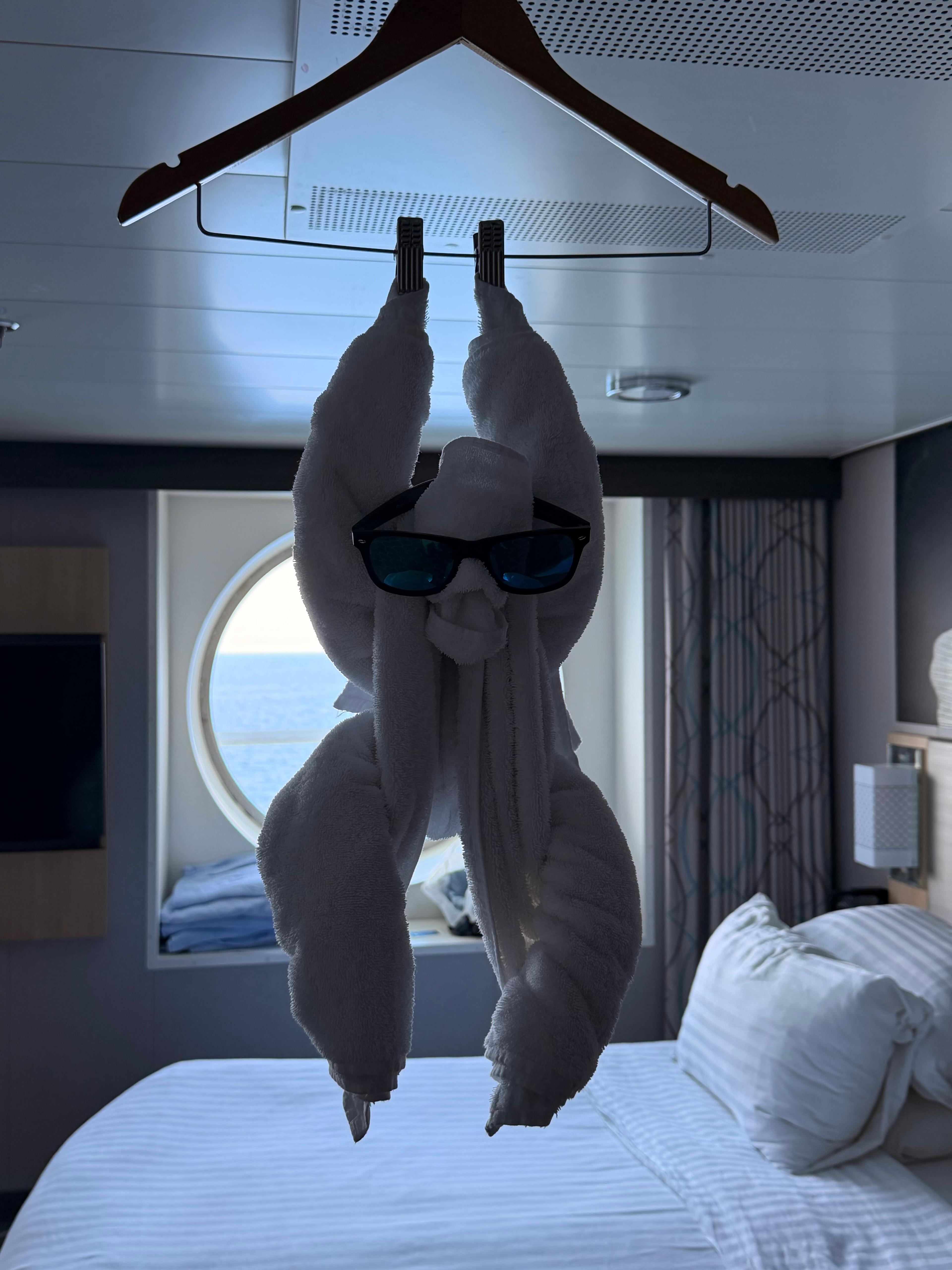 A towel monkey wearing sunglasses, arranged inside a cruise cabin