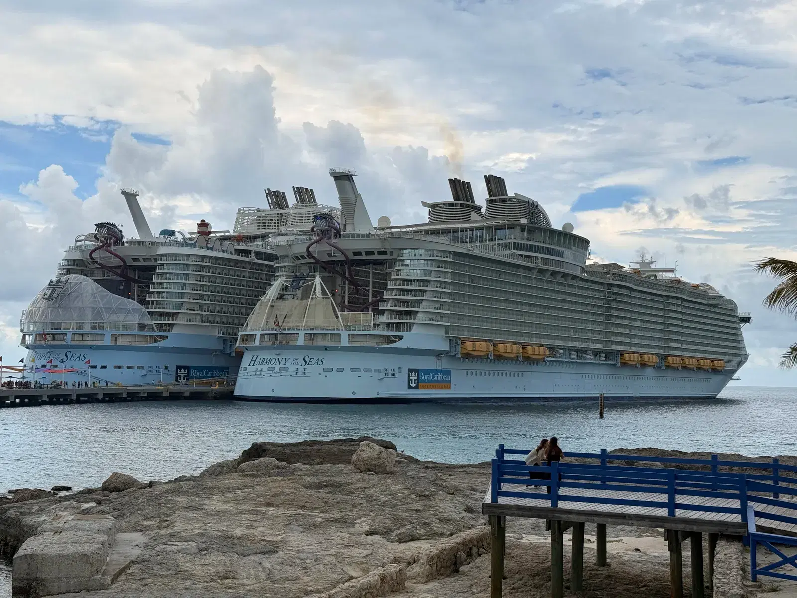 Harmony of the Seas and Utopia of the Seas docked together beneath a dramatic Caribbean sky