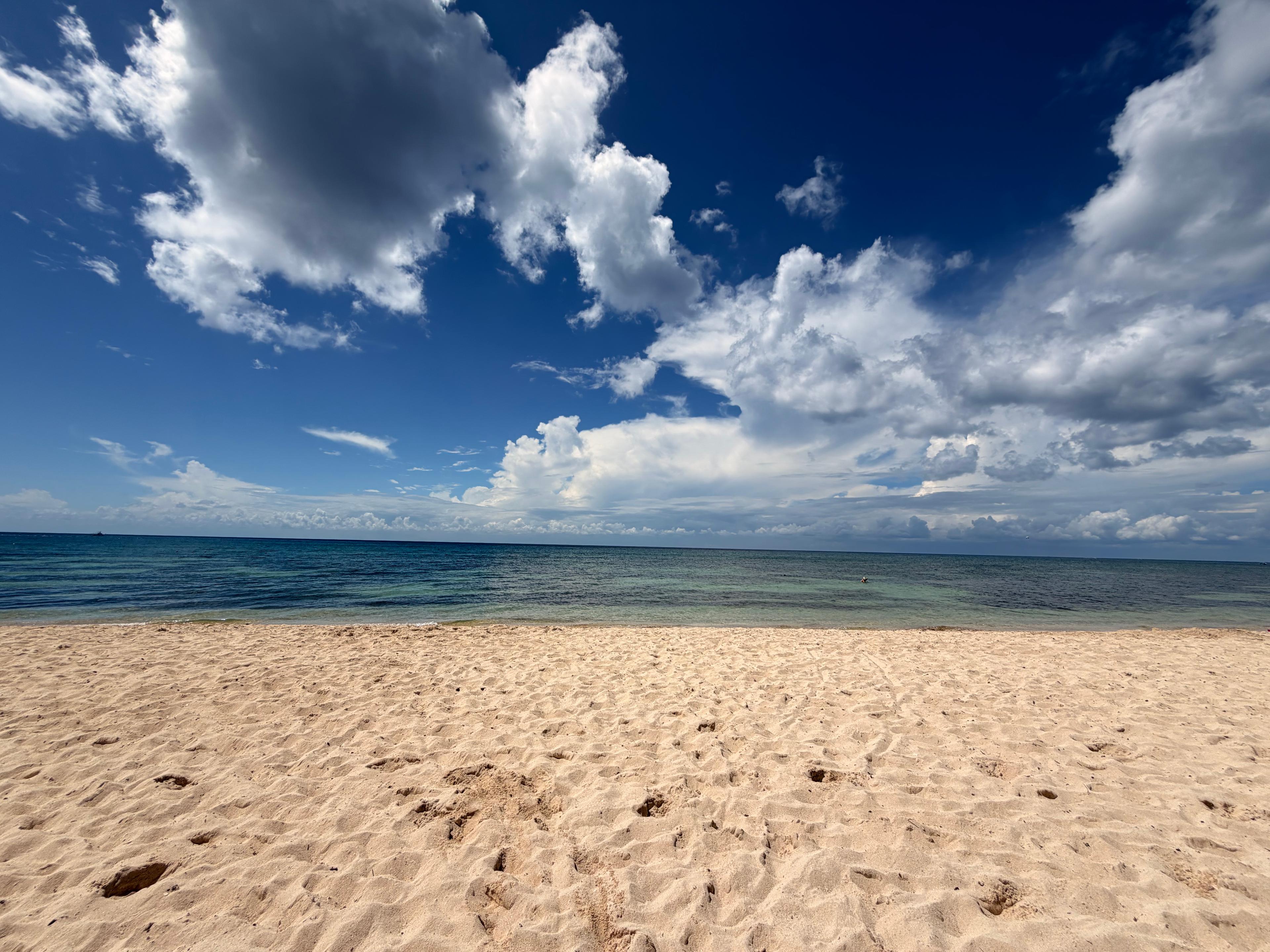 A sandy beach facing a calm ocean beneath a dramatic sky